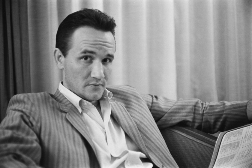 American singer-songwriter Roger Miller (1936-1992) wearing a striped blazer over a white shirt with the collar open, location unspecified, 1964. 