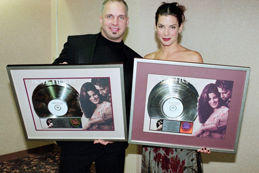 LOS ANGELES, CA - JANUARY, 1999: (L-R) American singer and songwriter Garth Brooks and American actress and producer Sandra Bullock pose for a portrait and hold a commemorative record for two million copies sold of the soundtrack for the movie "Hope Floats" circa January, 1999 in Los Angeles, California. 