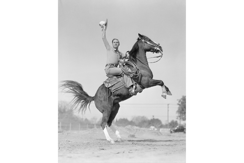 A natural horseman and one of the greatest trick riders to ever appear in motion pictures, Gene Autry Republic star, is just as much at home on a horse off the screen as on. He is shown here putting "Champion" his favorite mount, through some of his pages. Gene personally raises and trains all of his horses on his own ranch in the San Fernando Valley near Hollywood California.