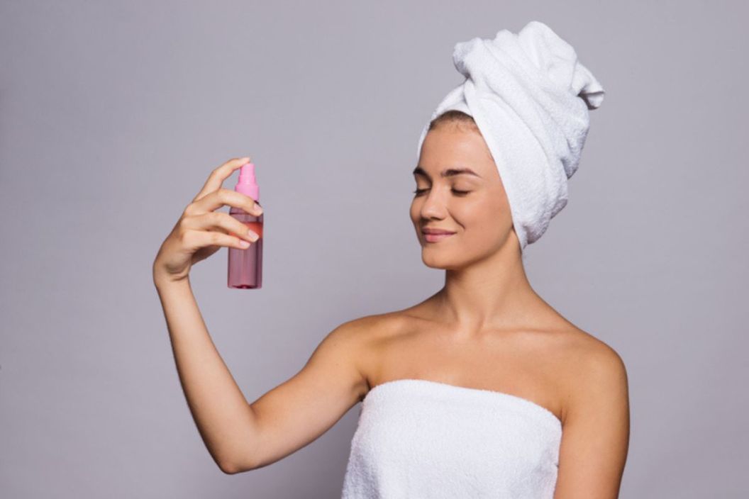 woman spraying face with setting spray