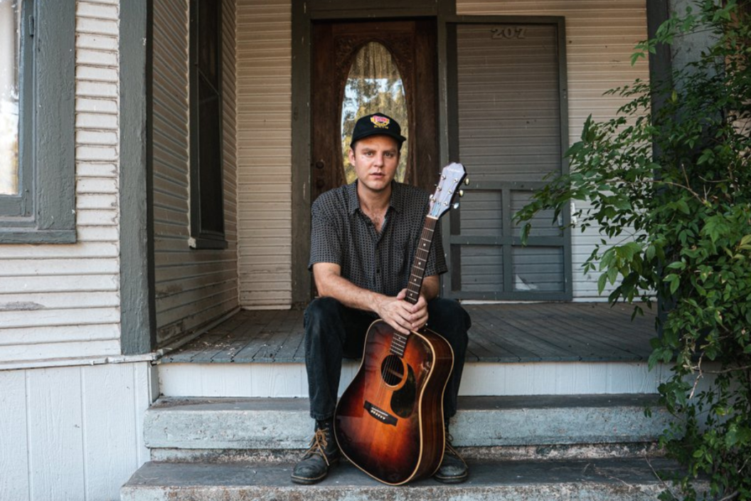 David Beck poses on porch with guitar