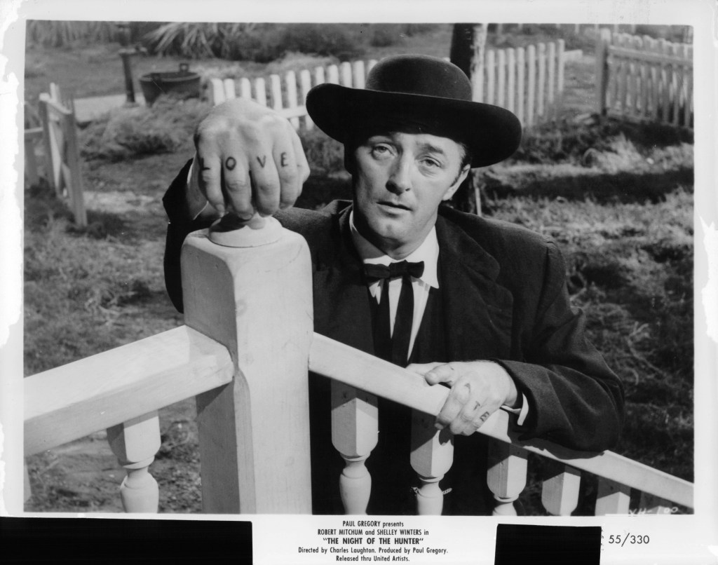 Robert Mitchum rests his tatooed hands on porch railing in a scene from the film 'The Night Of The Hunter', 1955.