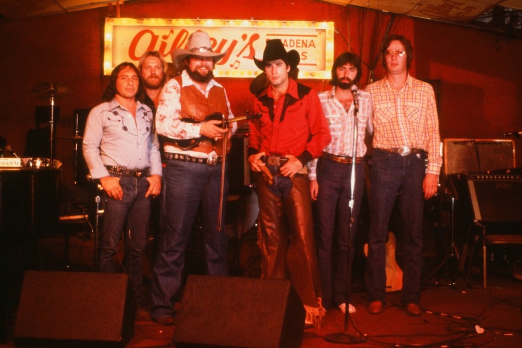 CIRCA 1980: Actor John Travolta poses with Charlie Daniels and his band on set of the Paramount Pictures movie 'Urban Cowboy" circa 1980.