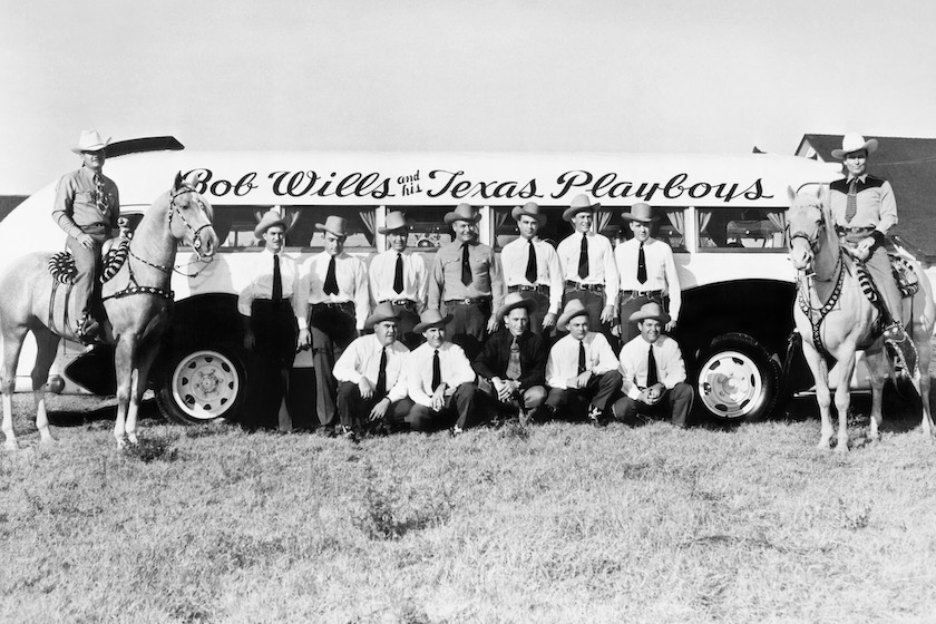 FRESNO, CA - OCTOBER 1945: Bob Wills and His Texas Playboys (L-R) Tommy Duncan (on horse). Standing: Louie Tierney, Les Anderson, Joe Galbreath (driver), Joe Holly, Billy Jack Wills, Harley Huggins. Crouching: Junior Barnard, Millard Kelso (driver), Johnnie Edwards, Alex Brashear and Bob Wills (on horse) pose for a portrait in front of their tour bus in October 1945 in Fresno, CA. 