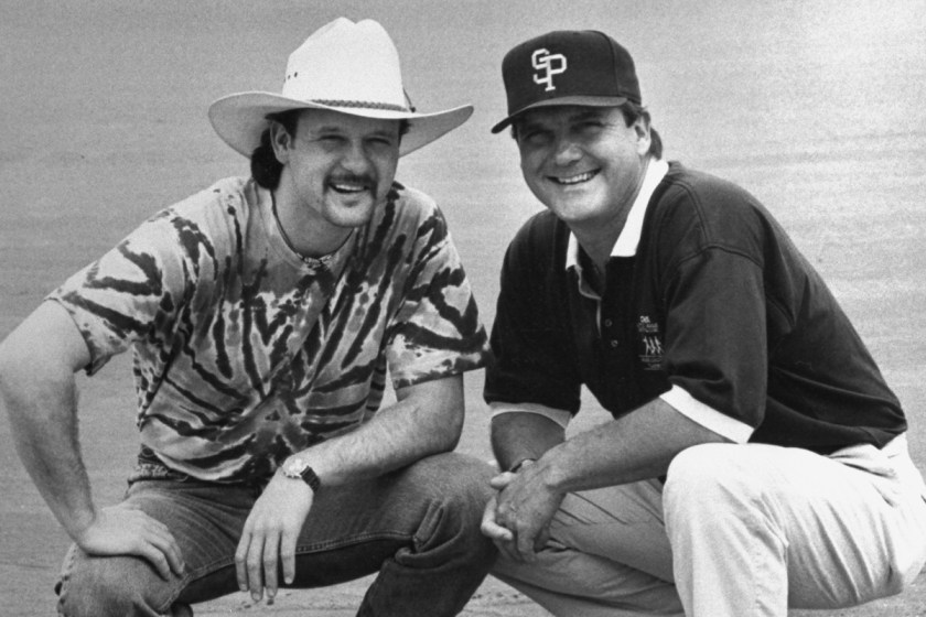 C&W musician Tim McGraw w. father, former baseball player Tug McGraw in baseball cap, as they crouch next to home plate on baseball field.