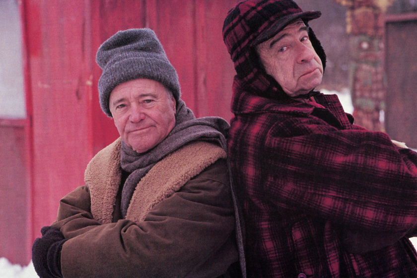 Jack Lemmon and Walter Matthau standing back to back outside in the snow in a scene from the film 'Grumpy Old Men', 1993