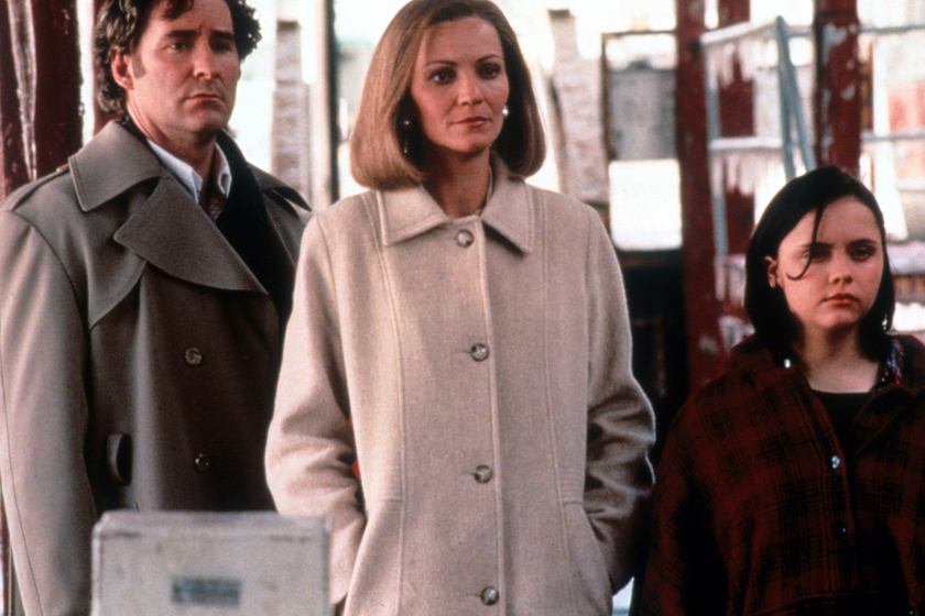 Kevin Kline, Joan Allen and Christina Ricci all standing on a sidewalk, wearing coats and staring in the same direction in a scene from the film 'The Ice Storm', 1997