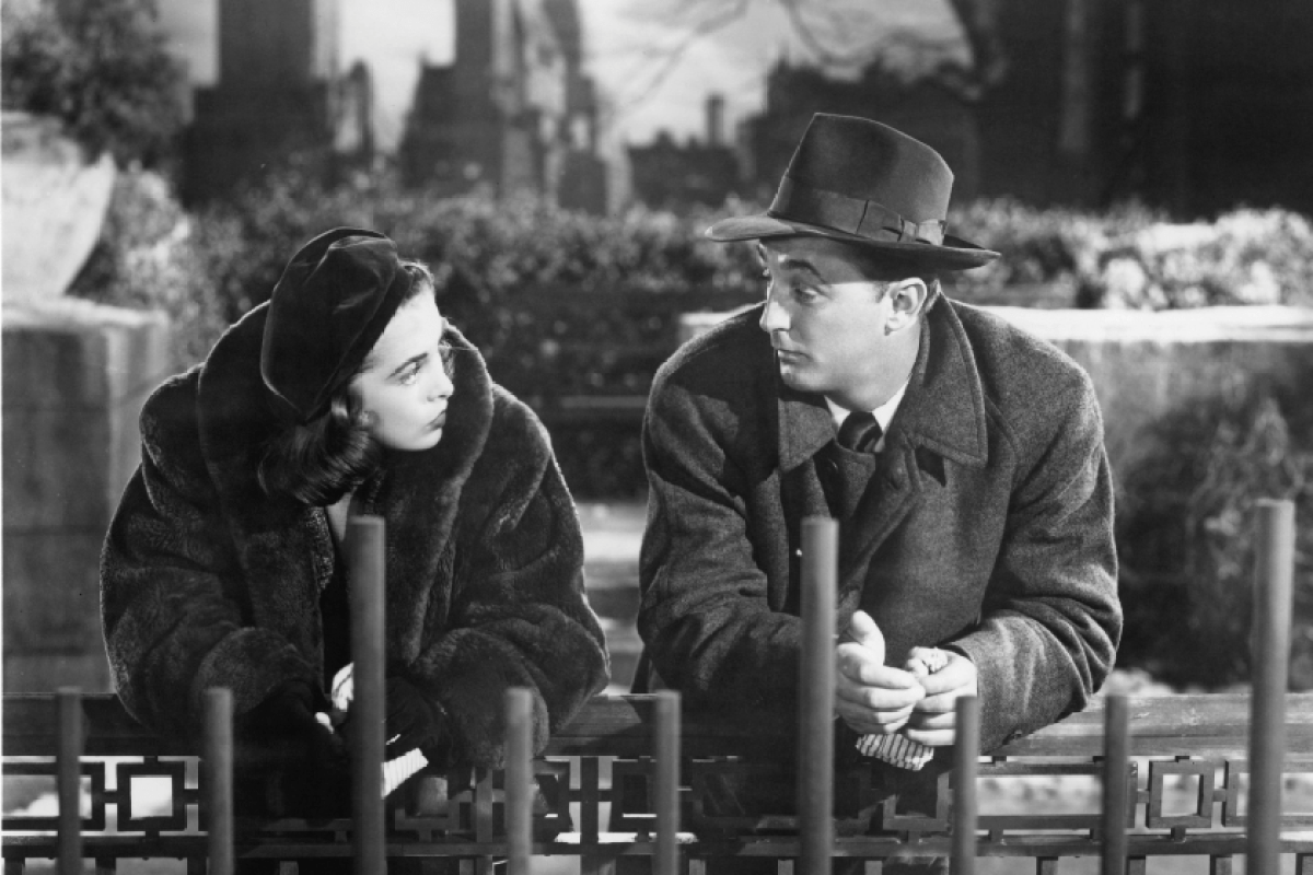 Janet Leigh leaning on gate talking to actor Robert Mitchum in a scene from the film 'Holiday Affair', 1949