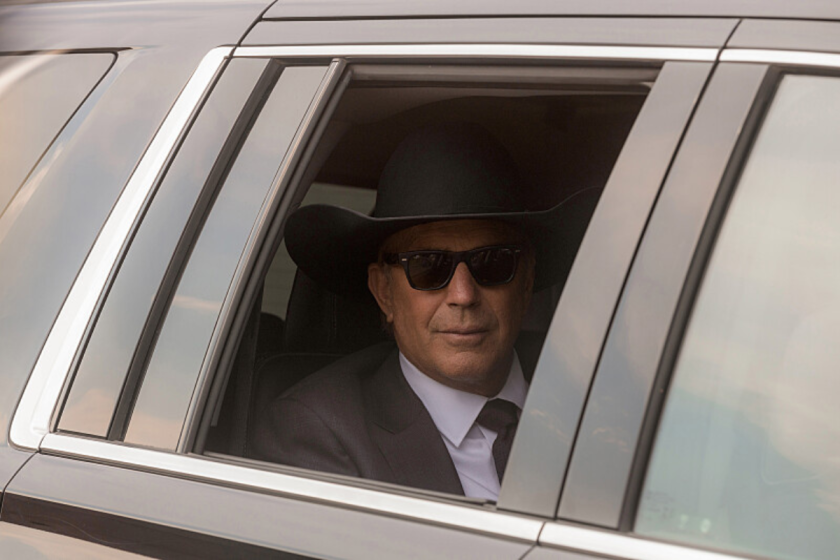 John Dutton rides in the back seat of a car in a scene from 'Yellowstone'