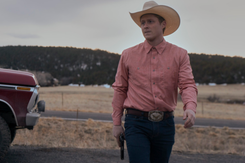Noah Reid (Billy Tillerson) walks along the road with a gun in 'Outer Range'
