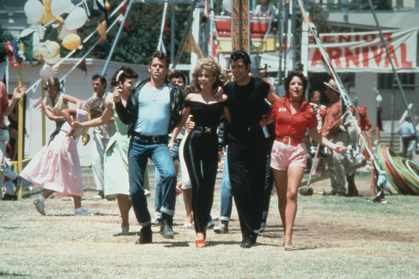Jeff Conaway, Olivia Newton-John, John Travolta and Stockard Channing walk arm in arm at a carnival in a still from the film, 'Grease' directed by Randal Kleiser
