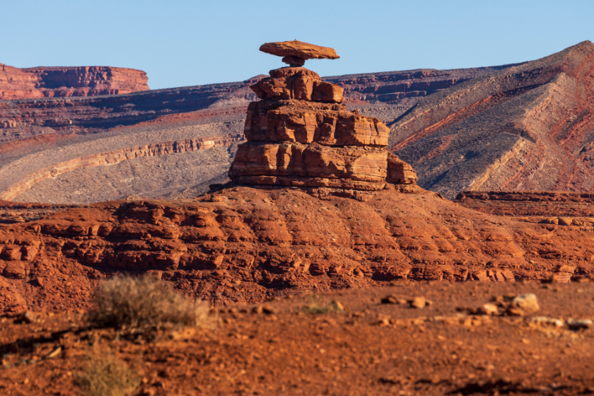 A scenic view of the barren landscape of Mexican Hat Rock in Utah, USA on a sunny day