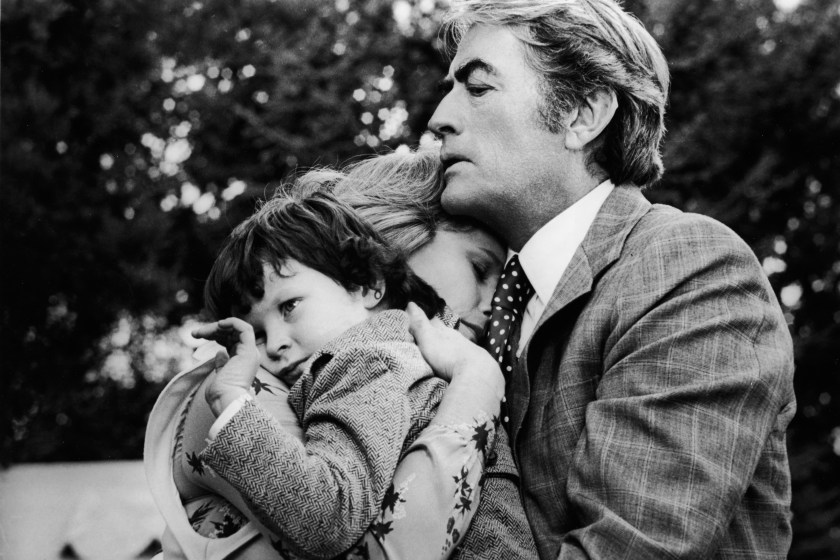 Actors Gregory Peck and Lee Remick embrace child Harvey Stephens in a still from the film, 'The Omen,' directed by Richard Donner, 1976.