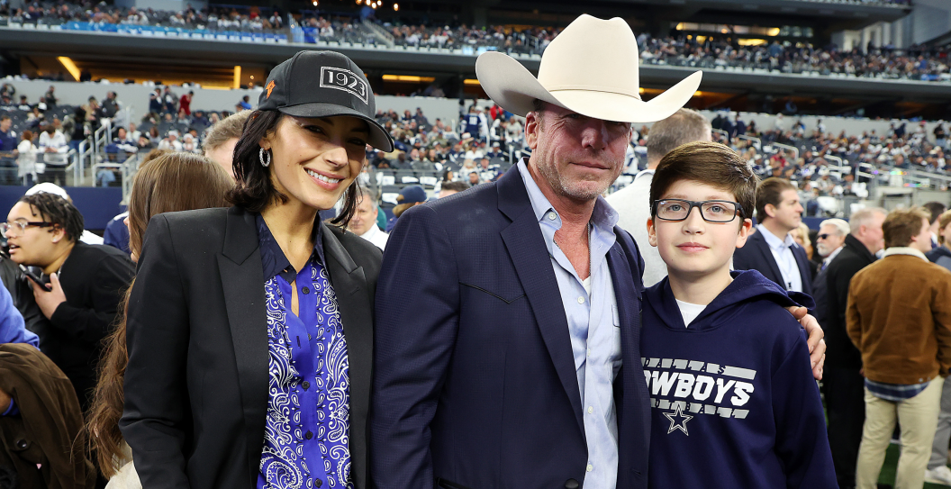 Nicole Muirbrook and Taylor Sheridan are seen withe their son Gus on the sidelines before the game between the Philadelphia Eagles and the Dallas Cowboys at AT&T Stadium on December 24, 2022 in Arlington, Texas