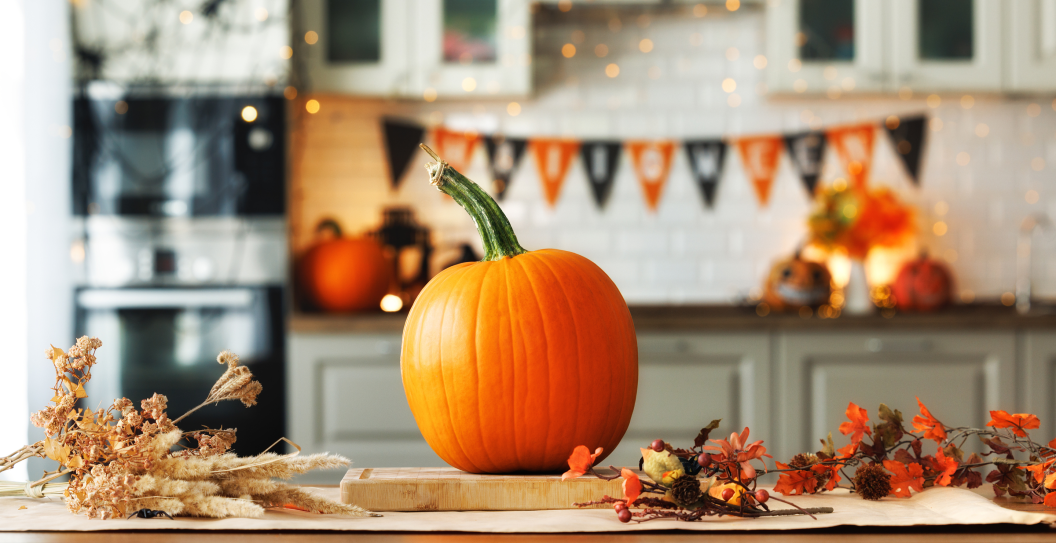 Autumn background for the Halloween holiday. Pumpkin on wooden table in kitchen. Halloween pumpkin decorations concept