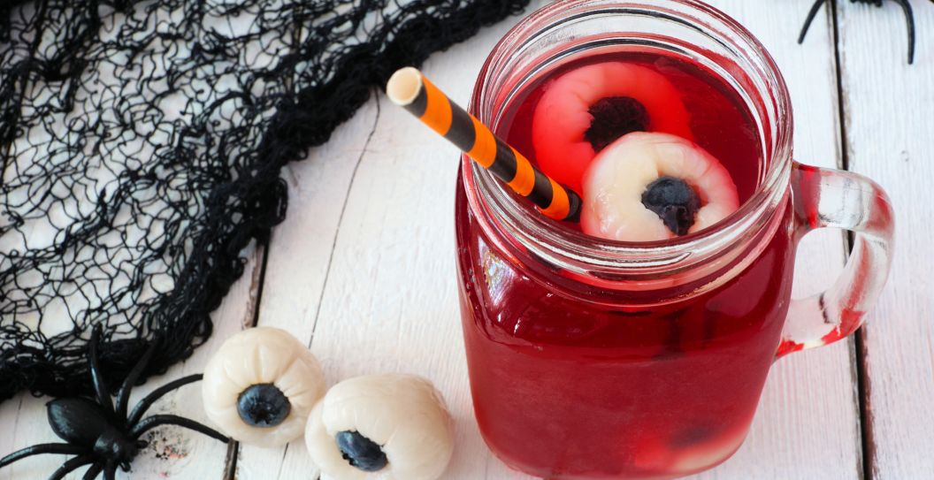 Creepy Halloween eyeball fruit punch in a mason jar against a white wood background