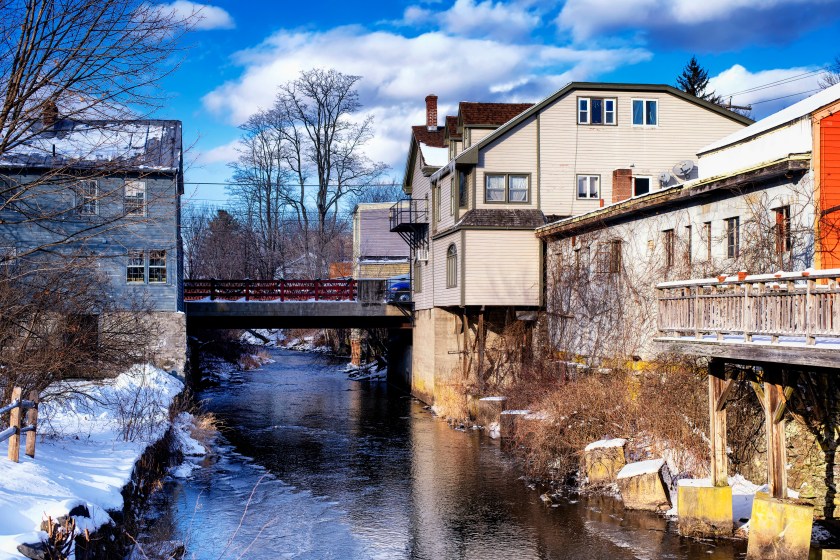 Old buildings lining the williams river running through the village of west stockbridge massachusetts on a sunny winter day.