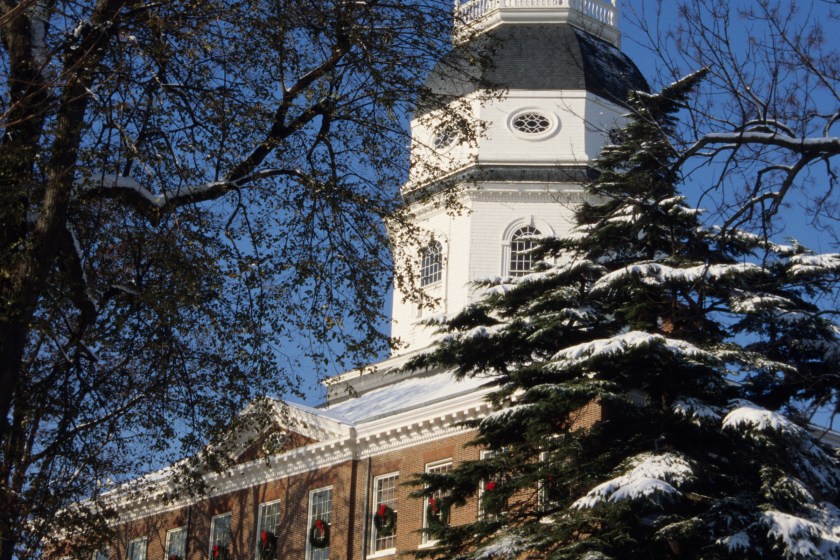 The Maryland Statehouse with snow and holiday wreaths.