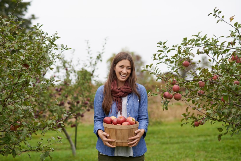 Shot of a young woman holding a container filled with freshly picked apples