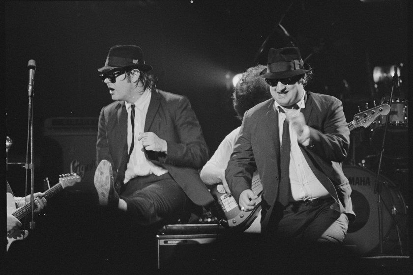 Dan Aykroyd and John Belushi performing on stage as the Blues Brothers. 