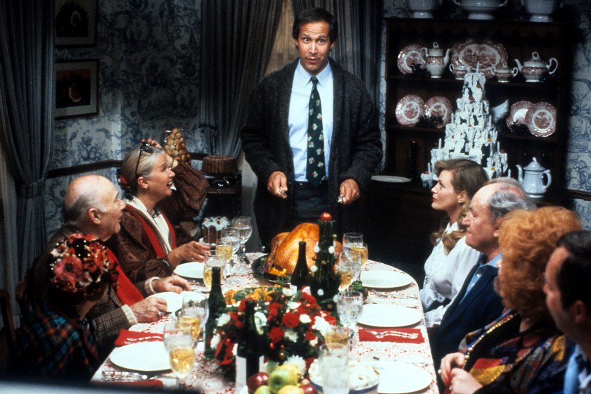 Chevy Chase stands at the head of the table in a scene from the film 'Christmas Vacation', 1989.