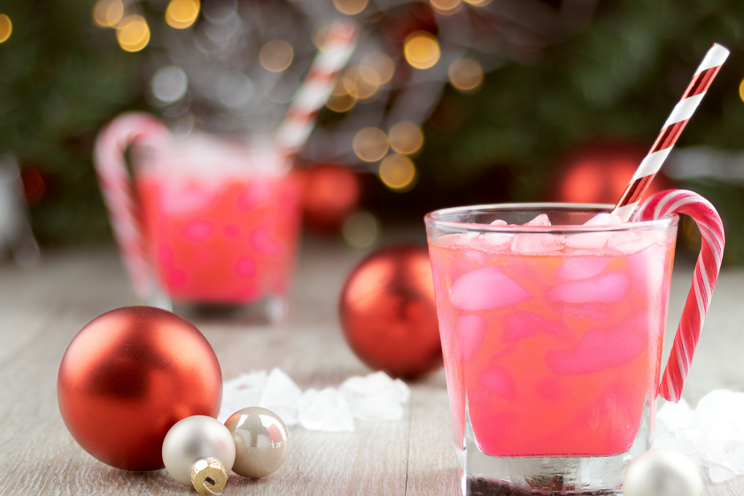 Two christmas party drinks with ice, straws and candy canes and sweets, copy space