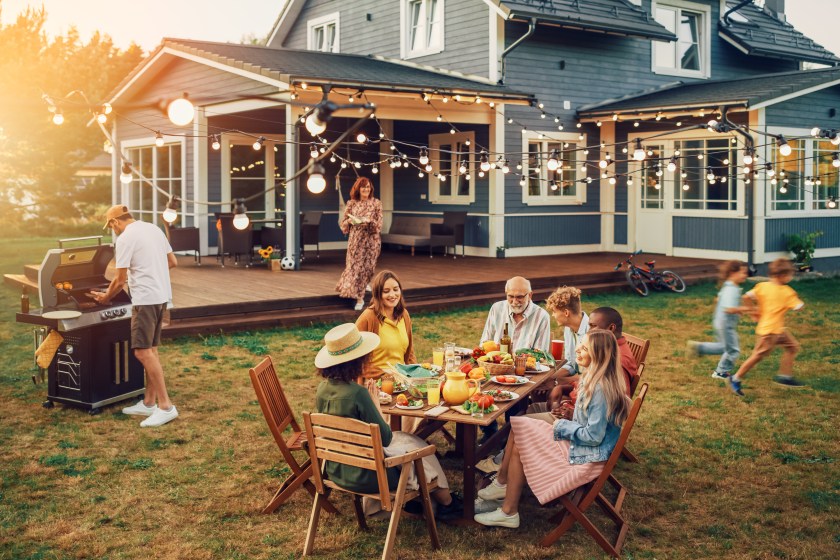 Big Family and Friends Celebrating Outside at Home. Diverse Group of Children, Adults and Old People Gathered at a Table, Having Fun Conversations. Preparing Barbecue and Eating Vegetables.