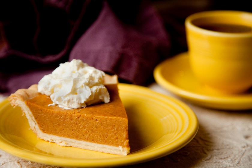 Pumpkin pie with whipped cream topping and cup of coffee