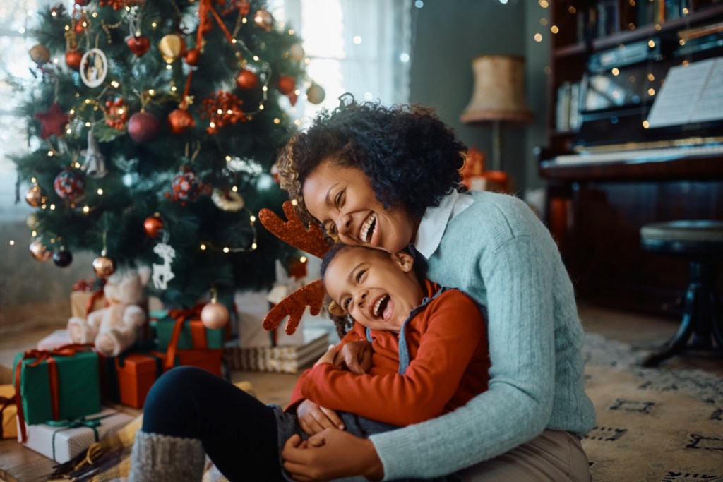 Happy African American mother and daughter laughing and having fun while spending Christmas together at home.