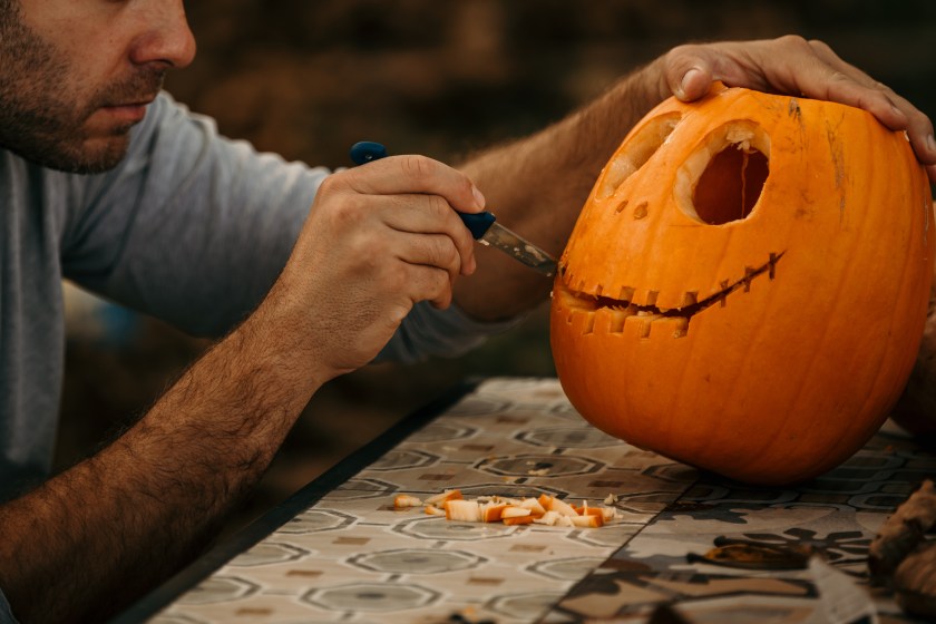 Man cutting and decorating a pumpkin for a Halloween.