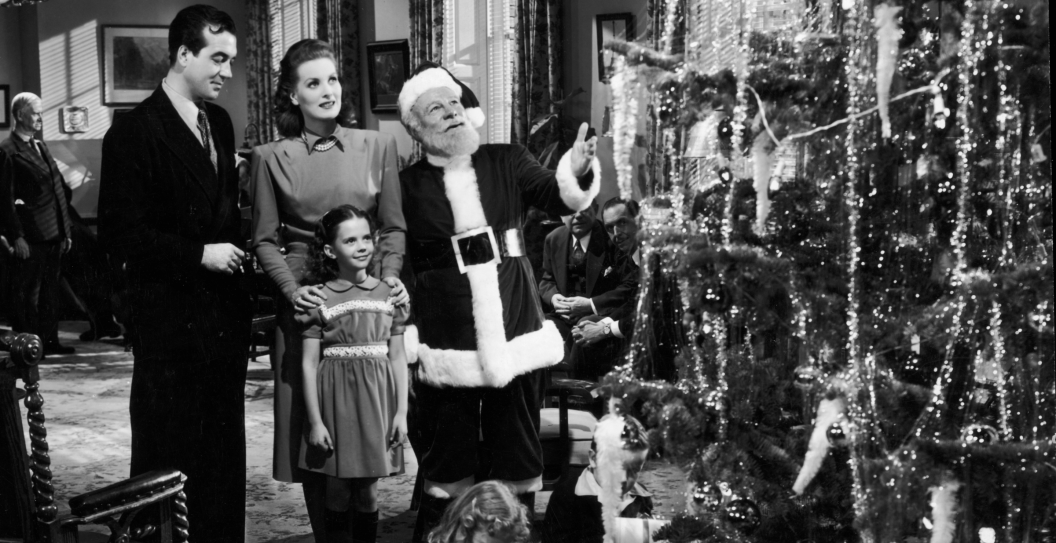 Actors John Payne, Maureen O'Hara, Edmund Gwenn (dressed as Santa Claus), and young Natalie Wood stand before a Christmas tree in a still from director George Seaton's film, 'Miracle on 34th Street.'