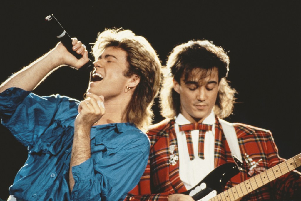George Michael (left) and Andrew Ridgeley of Wham! performing on stage.