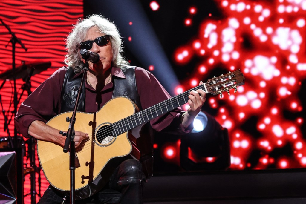 Jose Feliciano playing guitar in front of red lights.