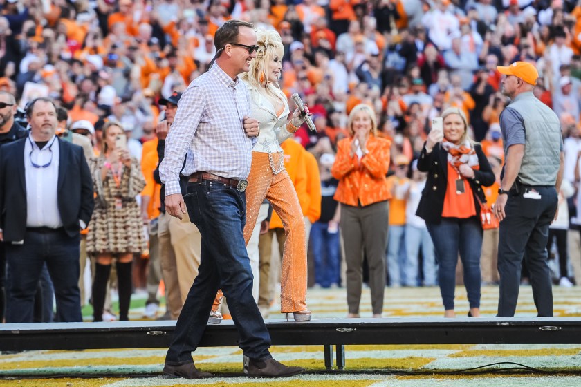 KNOXVILLE, TN - NOVEMBER 18: Peyton Manning walks with Dolly Parton during a college football game between the Tennessee Volunteers and the Georgia Bulldogs on November 18, 2023, at Neyland Stadium, in Knoxville, TN.