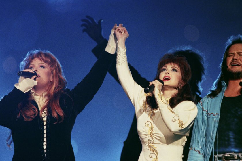 ATLANTA, GA - 1994: Country singers Wynonna Judd (left), Naomi Judd and Travis Tritt perform during the half-time show at the 1994 Atlanta, Georgia, Superbowl XXVII football game at the Georgia Dome.