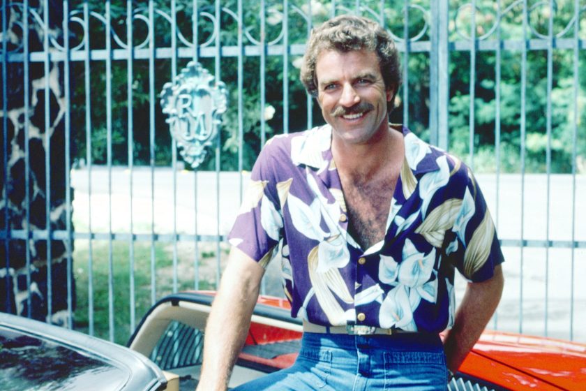 Tom Selleck as the titular investigator in the television series 'Magnum, P.I.', circa 1985. He is posing with his red Ferrari 308. 