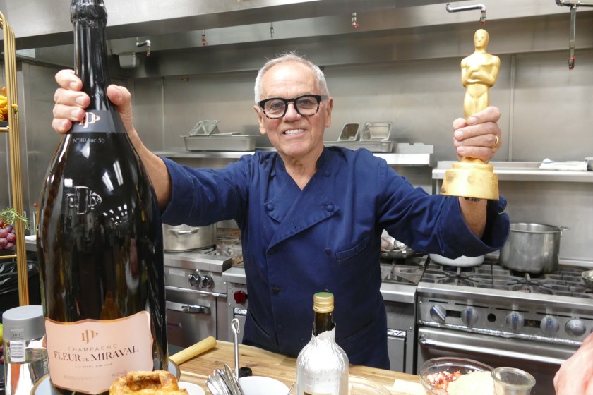 08 March 2023, USA, Los Angeles: Star chef Wolfgang Puck stands in a kitchen with an imitation Oscar statue and a huge bottle of champagne. Puck is serving up food for the 29th time after the Oscar gala for the celebrity guests - this time, too, he has made provisions for the big appetite. (to dpa "Star chef Wolfgang Puck: "Everyone gets an Oscar from me") Photo: Barbara Munker/dpa 