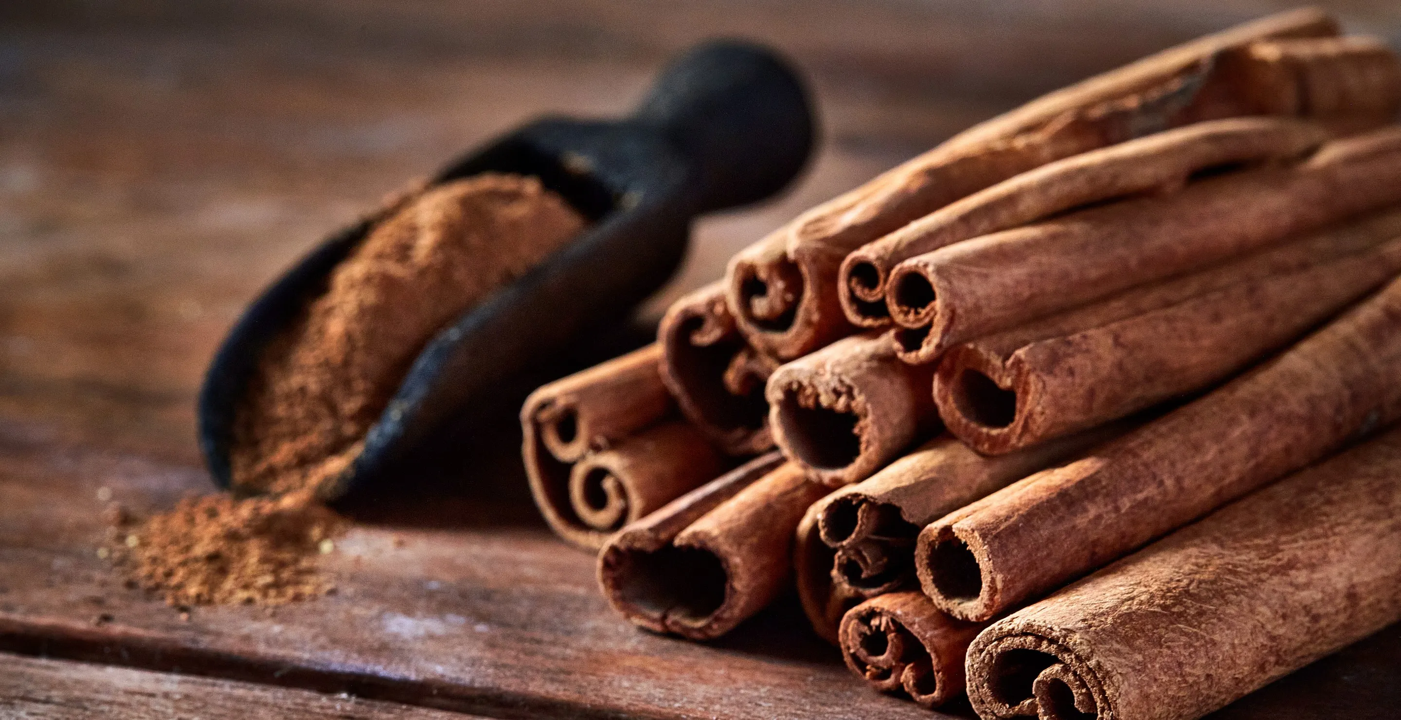 Stick cinnamon and cinnamon powder on rustic wooden table.