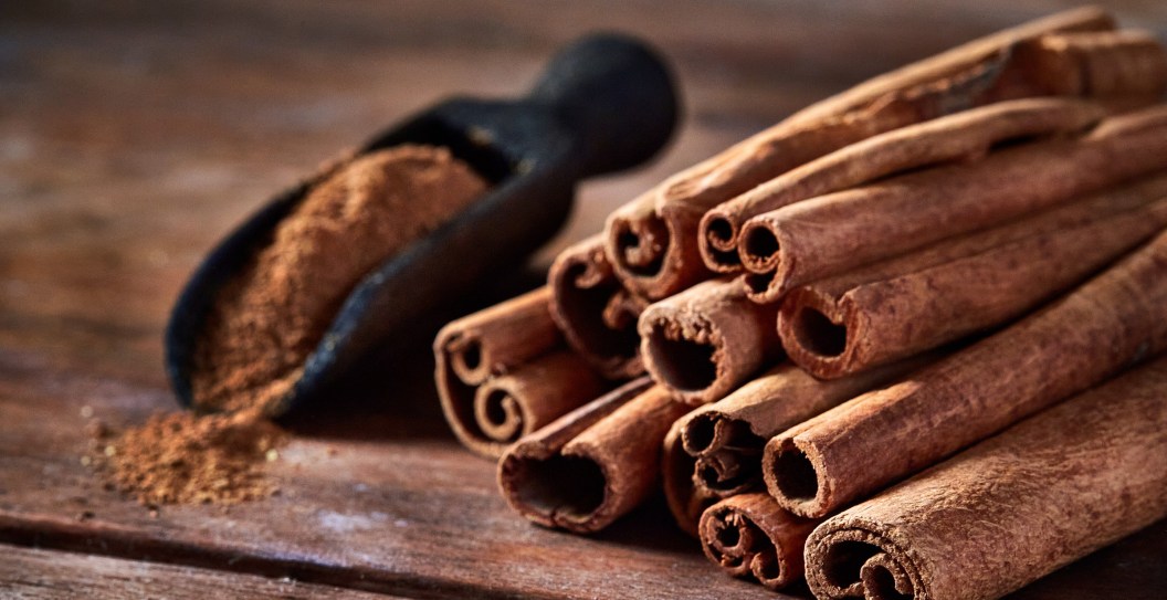 Stick cinnamon and cinnamon powder on rustic wooden table.