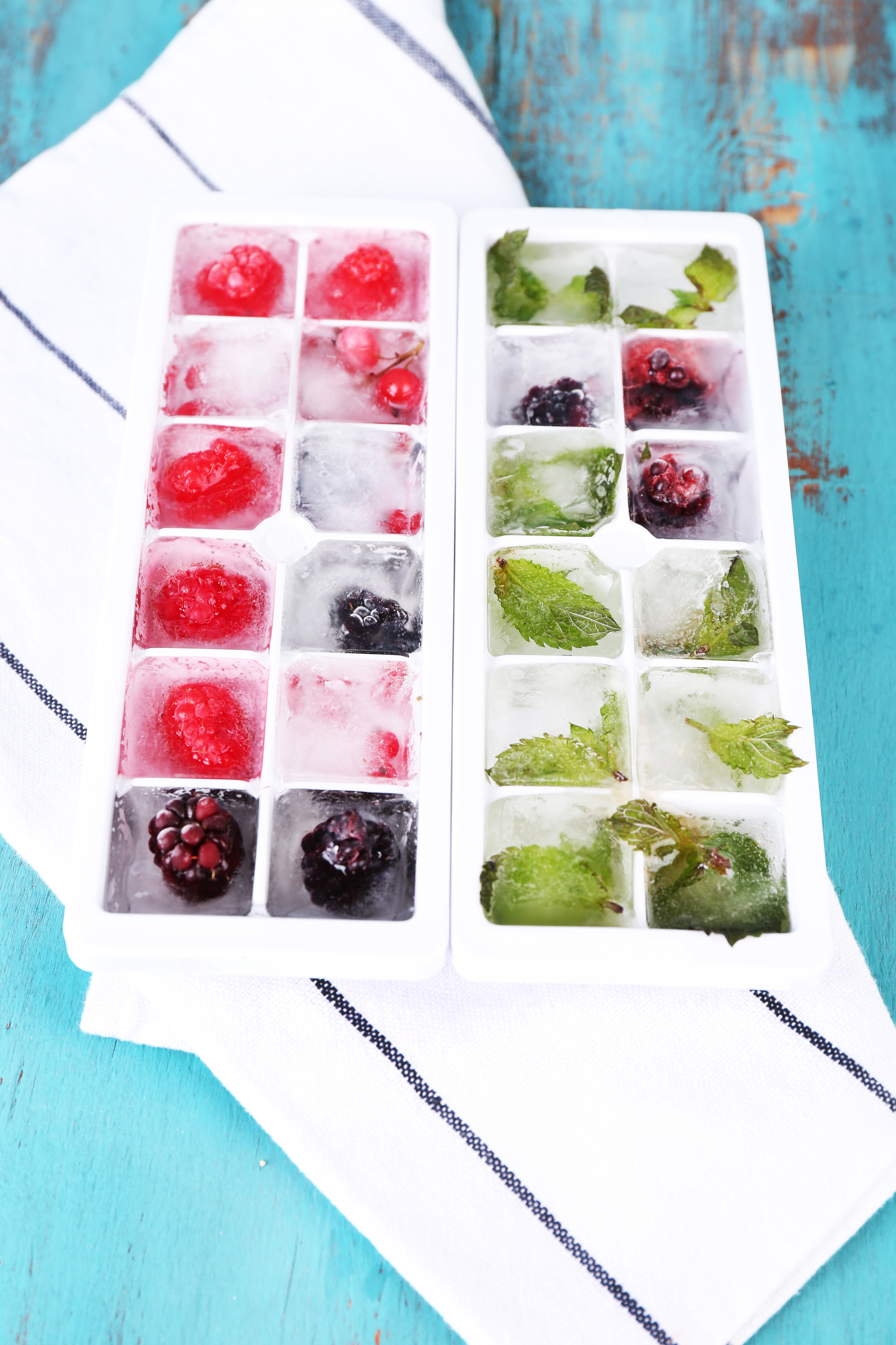 Ice cubes with forest berries, mint leaves in ice cube tray,