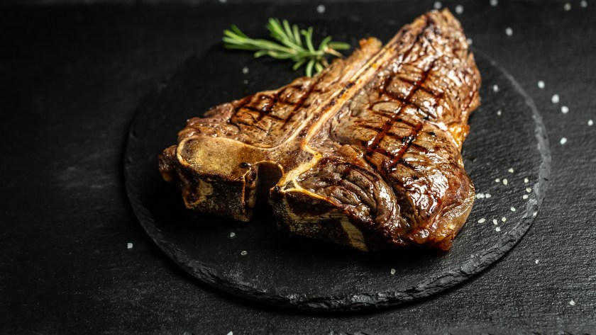 T-bone or aged wagyu porterhouse grilled beef steak with spices and herbs. Gourmet grilled and sliced porterhouse steak. Food recipe background. Close up