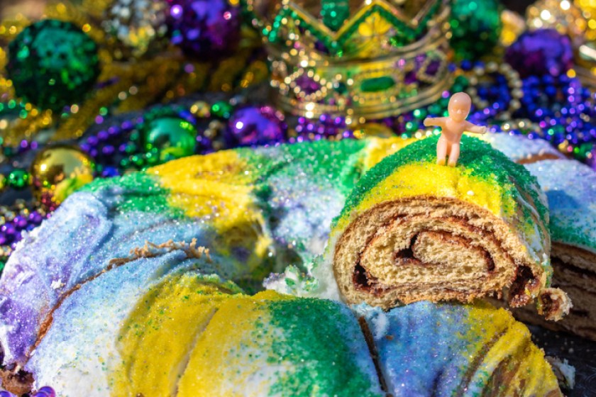 Sliced Mardi Gras King Cake topped with toy baby