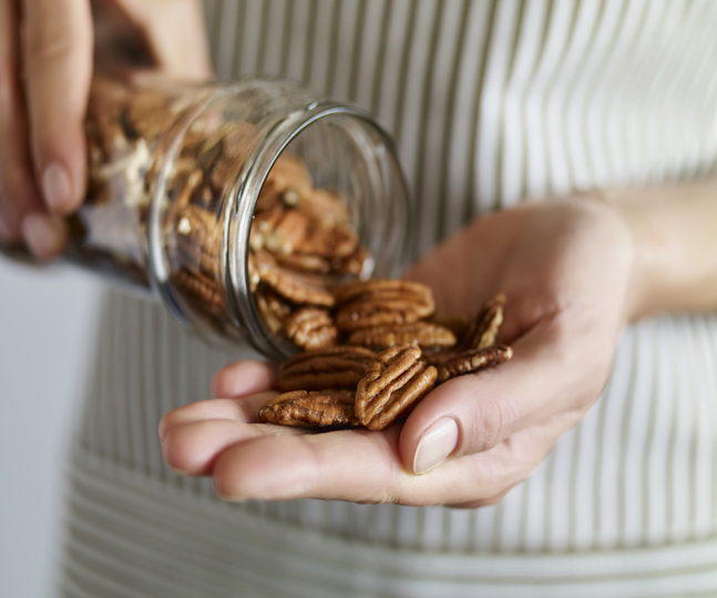 Close up shot of a woman taking pecans from a glass jar