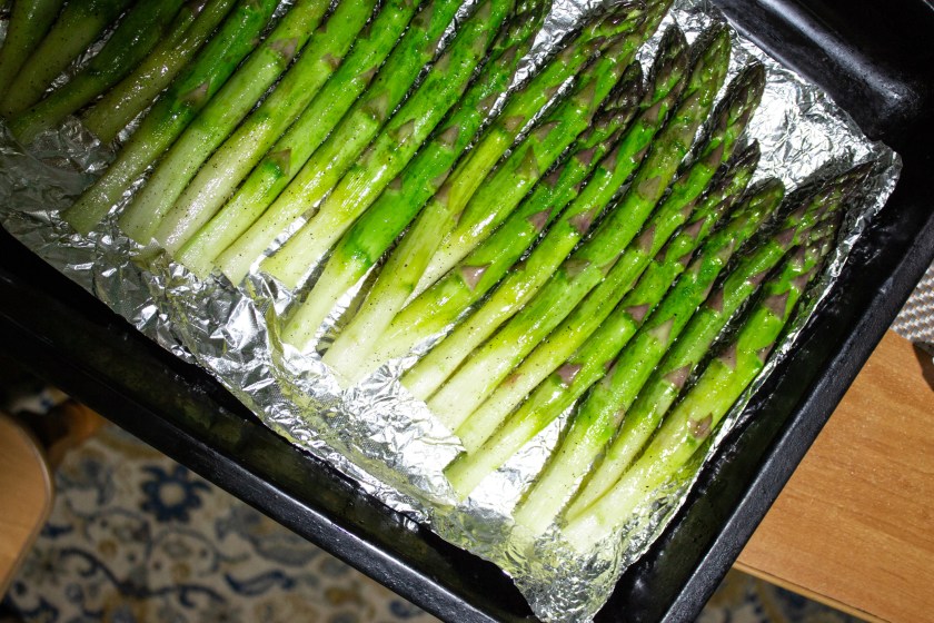 Green asparagus on a baking sheet. Ripe healthy fresh asparagus on foil top view. Healthy organic food. Cook at home. Proper nutrition. Natural vitamins, raw materials for food