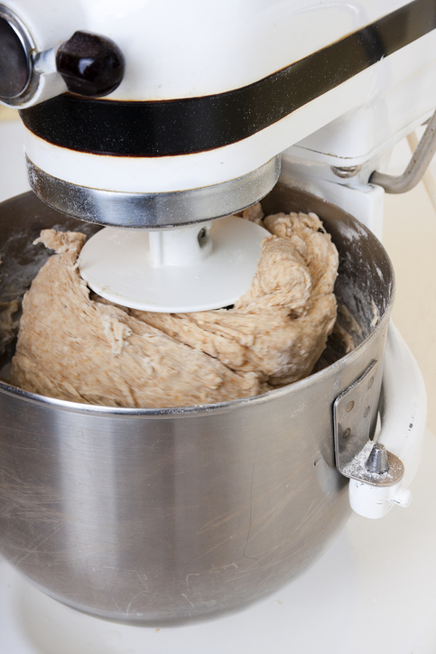Bread dough being mixed in a heavy duty mixer.