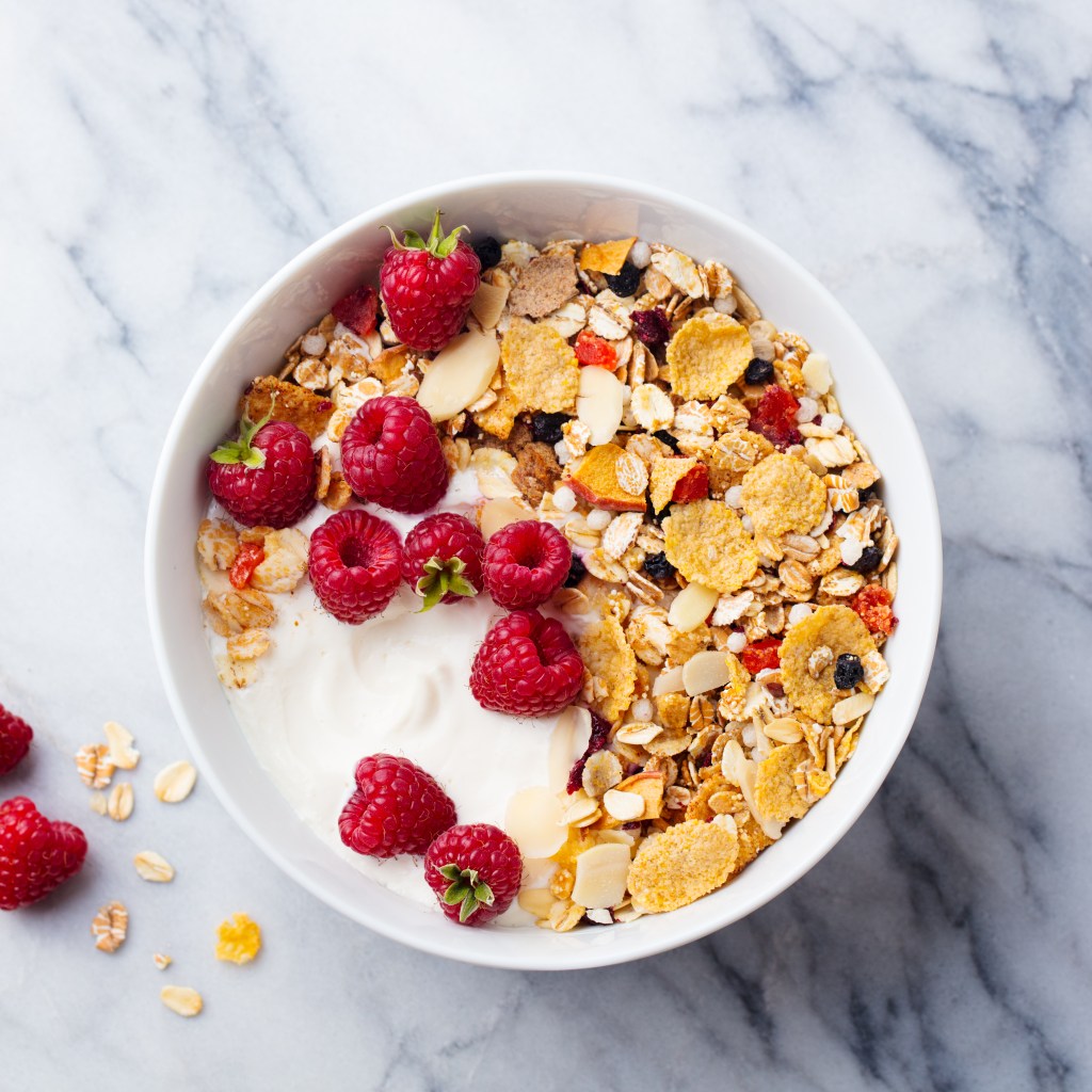 Healthy breakfast. Fresh granola, muesli with yogurt and berries. Marble background. Top view.