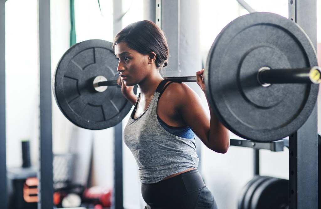 woman working out with a barbell at the gym