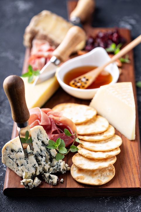 Cheese and snack board with crackers and prosciutto