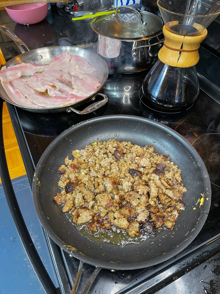 cooking sausage and bacon in a pan