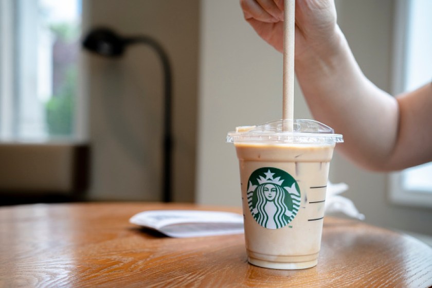 A customer is using a paper straw to drink a cold Starbucks